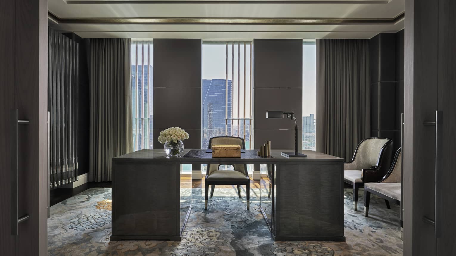 Sophisticated office space with a dark wooden desk, leather chair, floral centerpiece and large windows showcasing a city skyline view