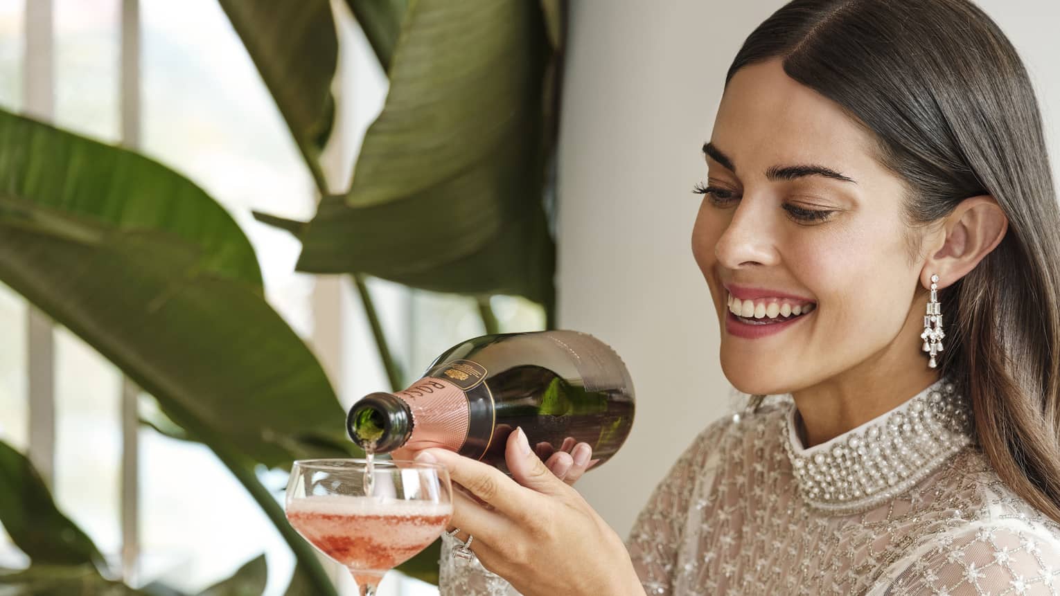 A woman pouring wine down a pyramid of glasses.