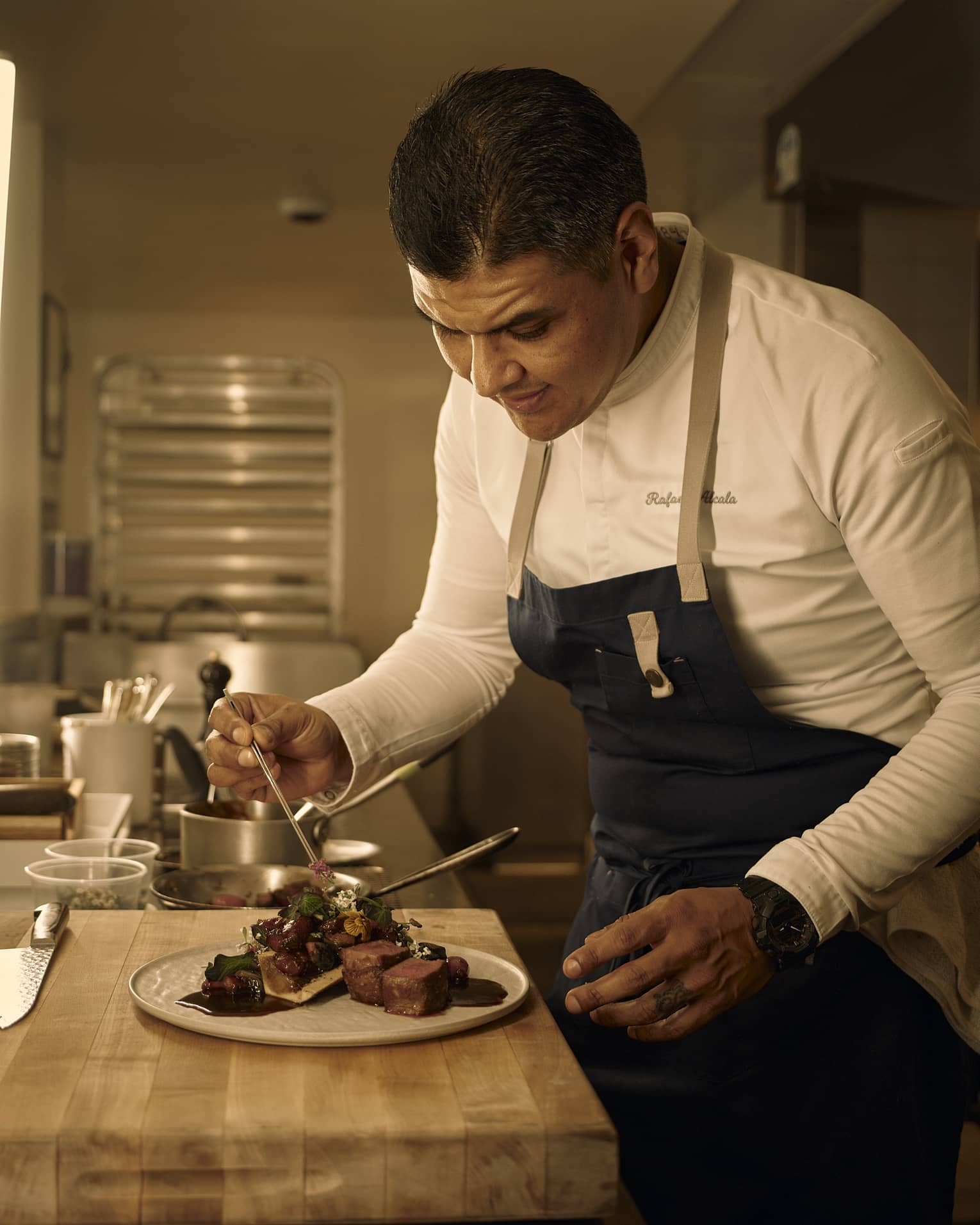 Chef places garnish onto a steak dish