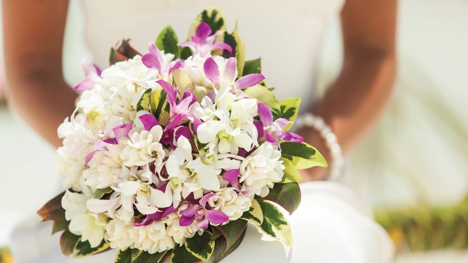 Close-up of bride holding wedding bouquet with purple and white flowers
