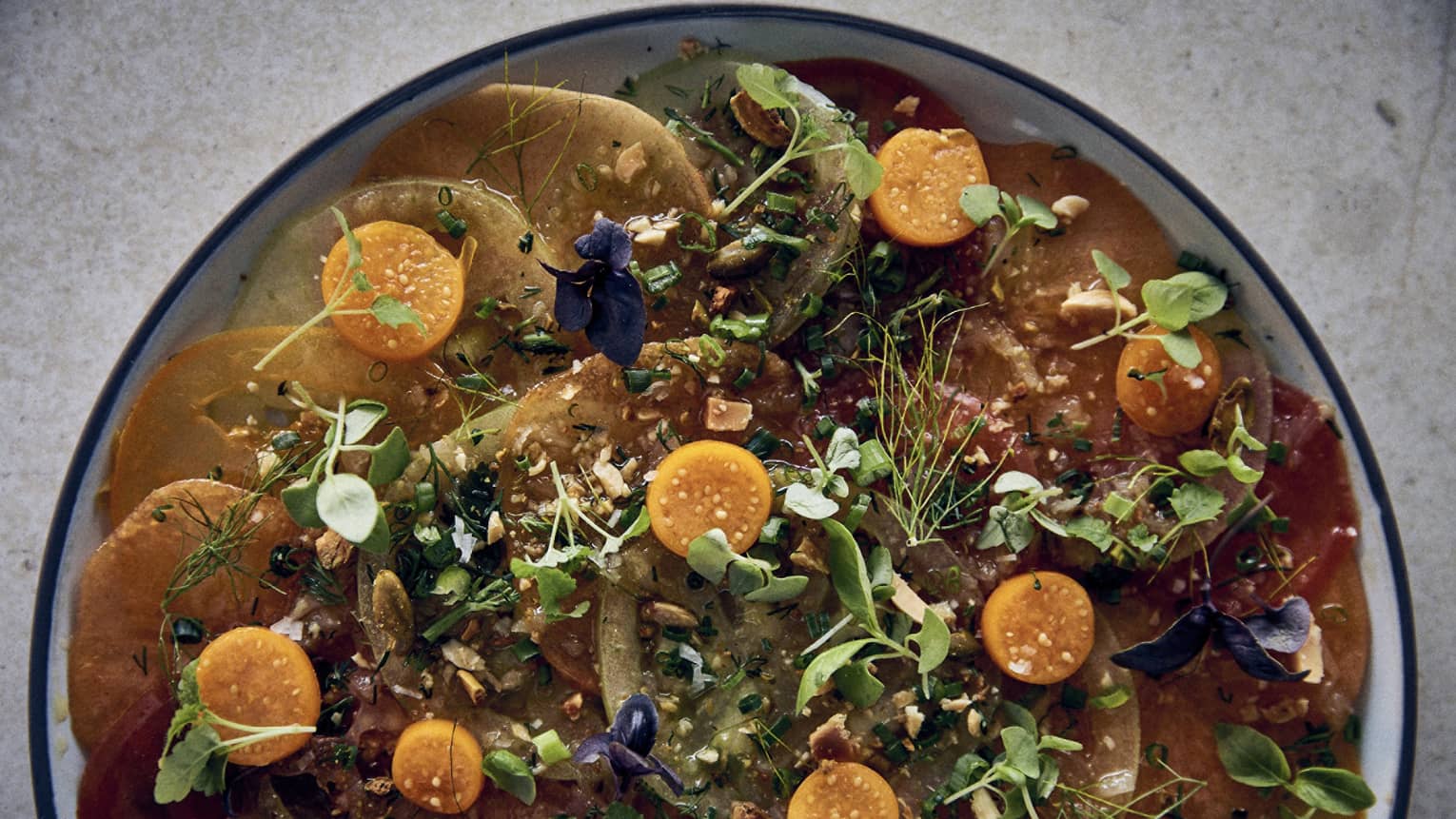 Heirloom tomato carpaccio in a white, blue-rimmed stoneware bowl