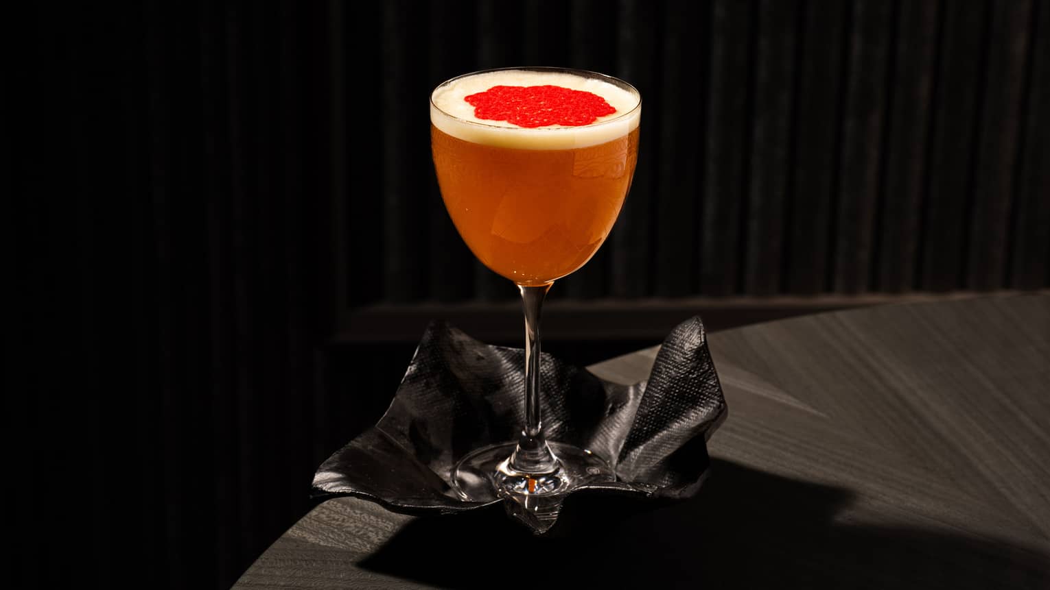 Bright orange?hued cocktail with a red garnish served in a stemmed glass