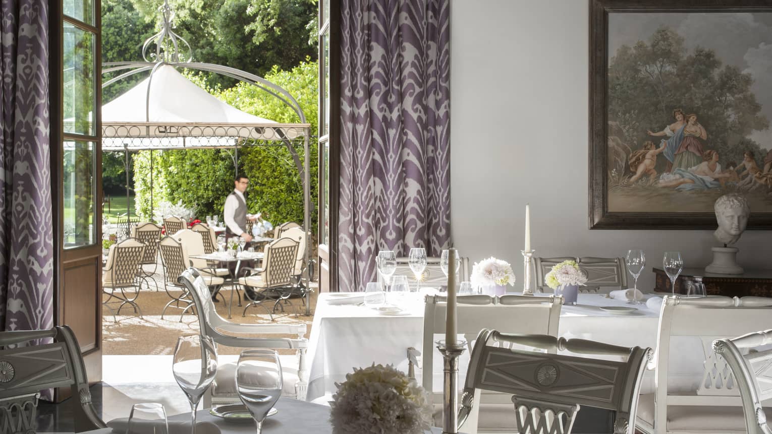 Il Palagio formal dining tables with flowers, candles, open doors to patio, server