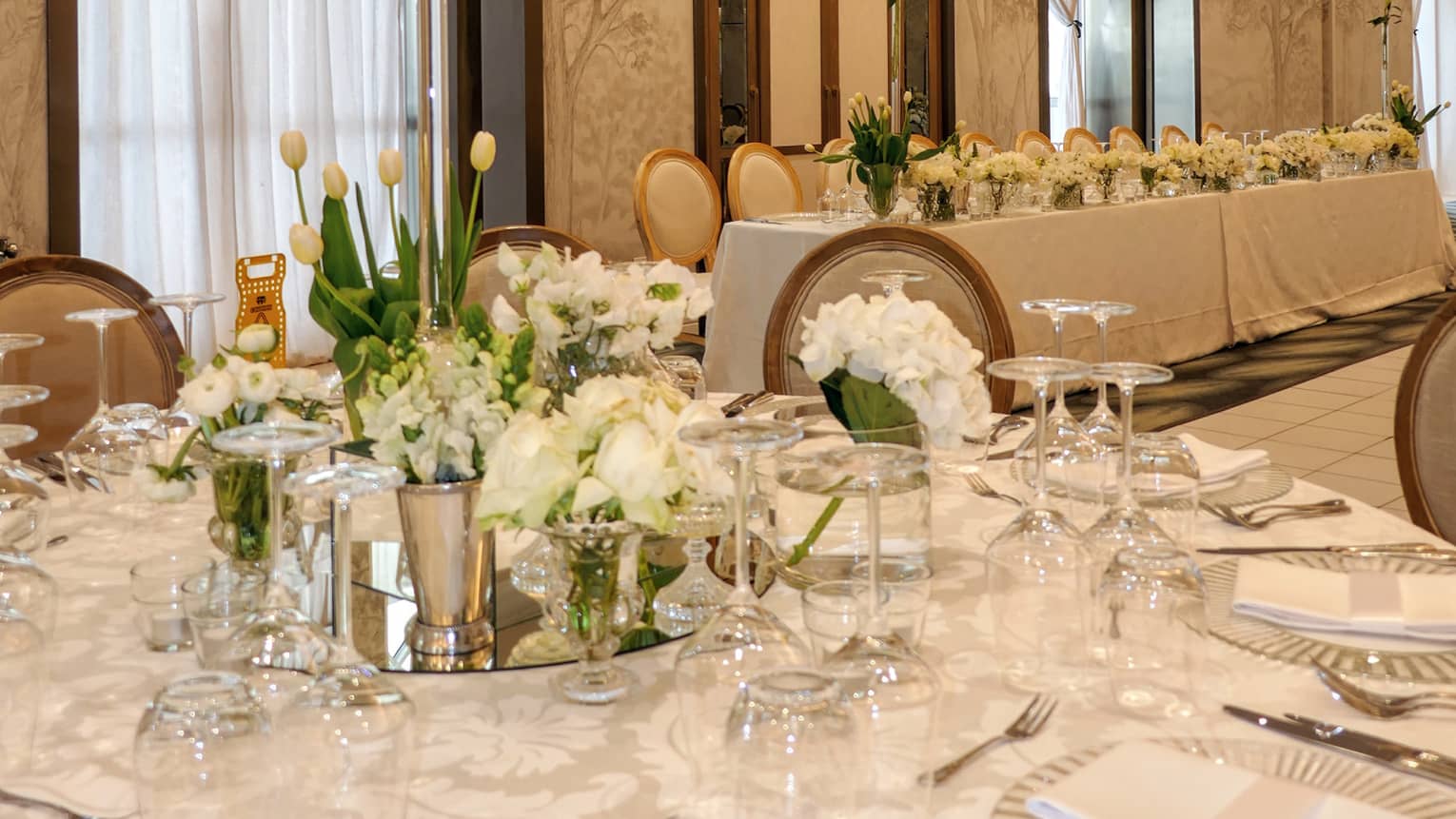 A spacious ballroom with tables set for an event meal, including floral decor and centrepieces