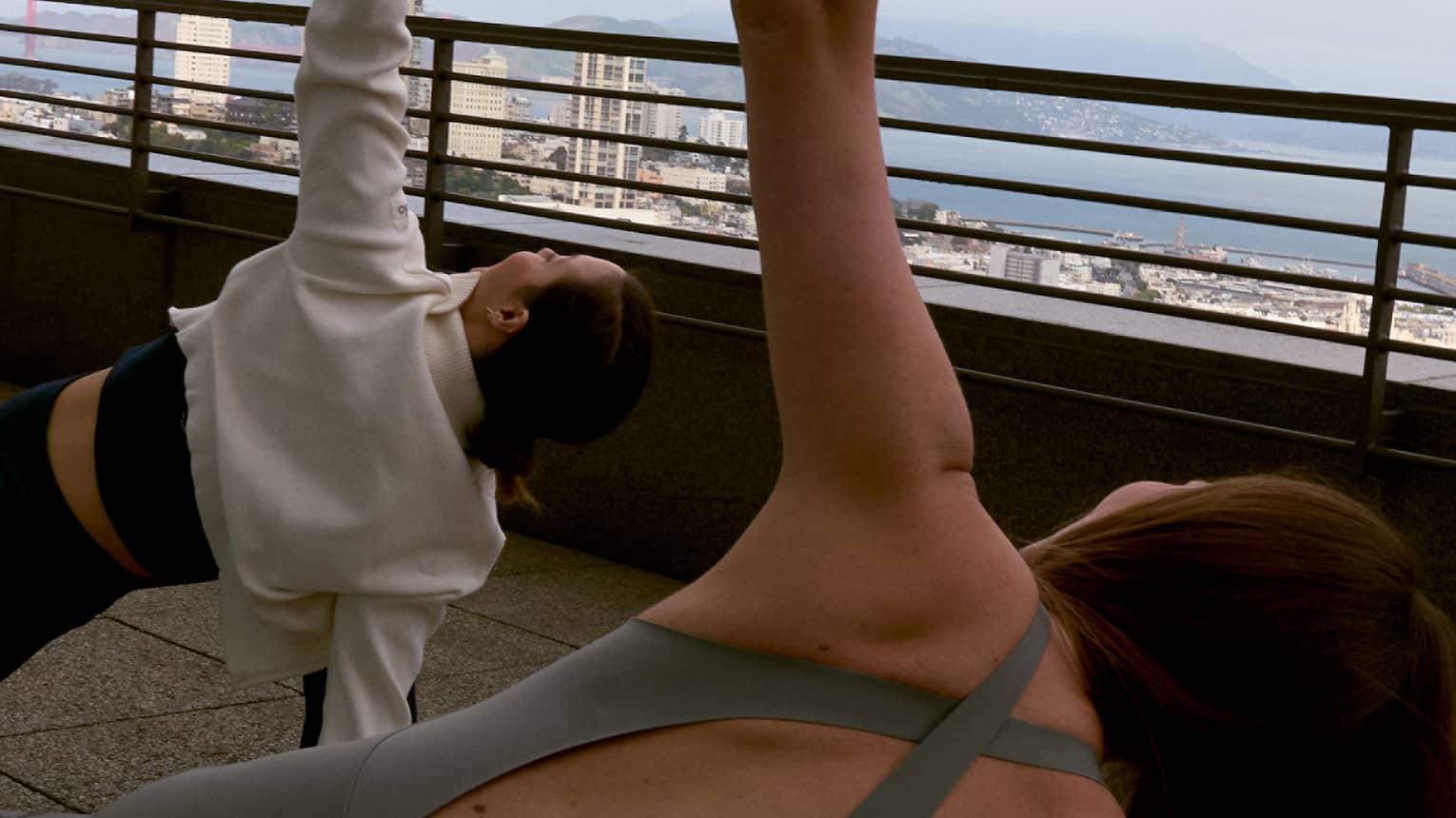 Two guests doing yoga on a rooftop with the sky in the background