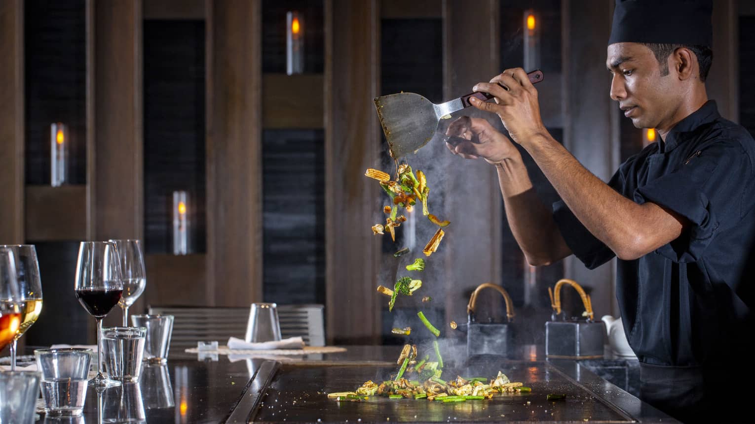  A four seasons dining staff working on a towering dish made of vegetables at the bar