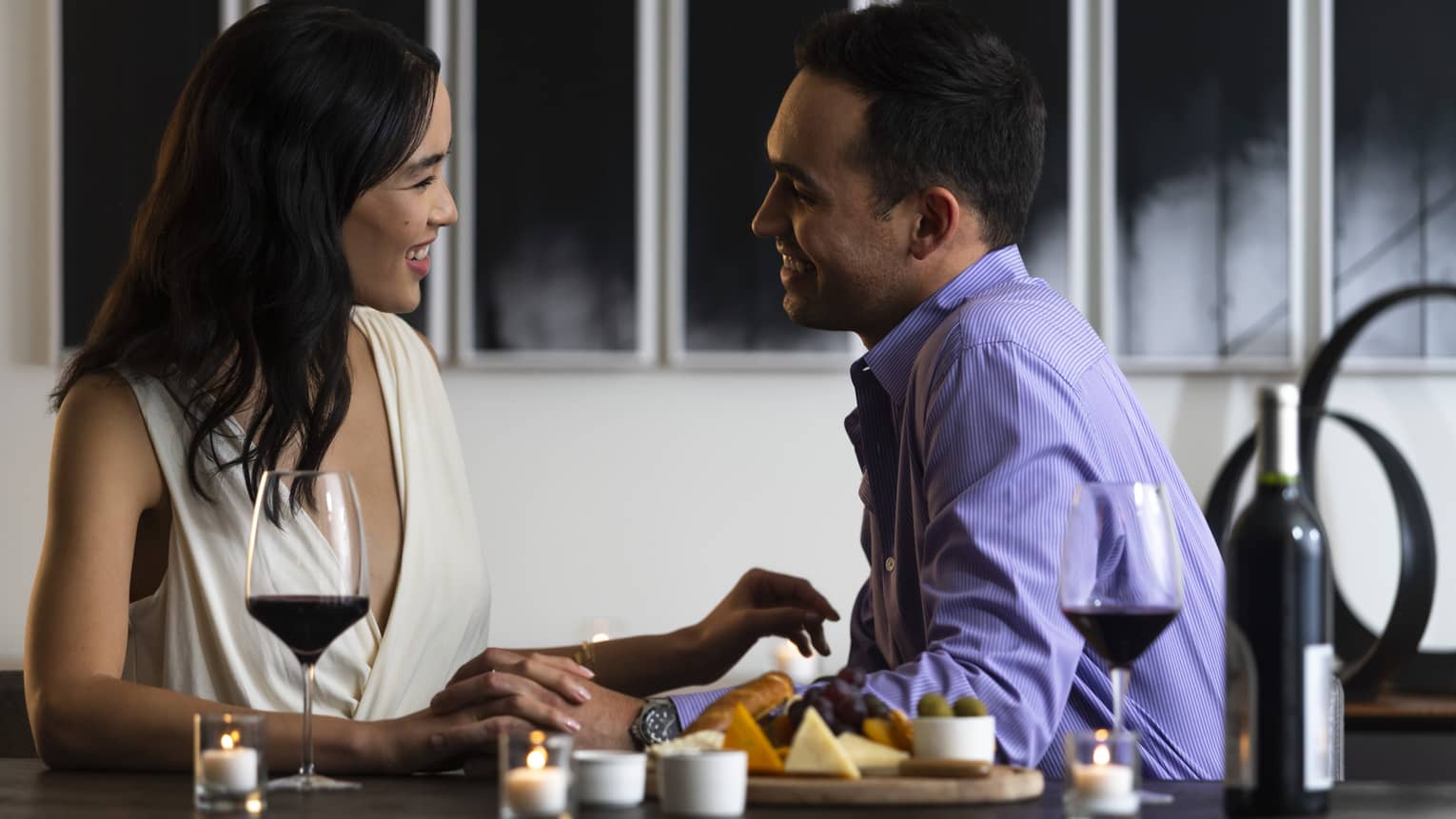 A man and woman enjoying a selection of small foods and wine.
