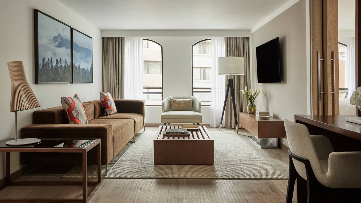Four Seasons Executive Suite light-filled living room with brown sofa, white chairs, wood tables