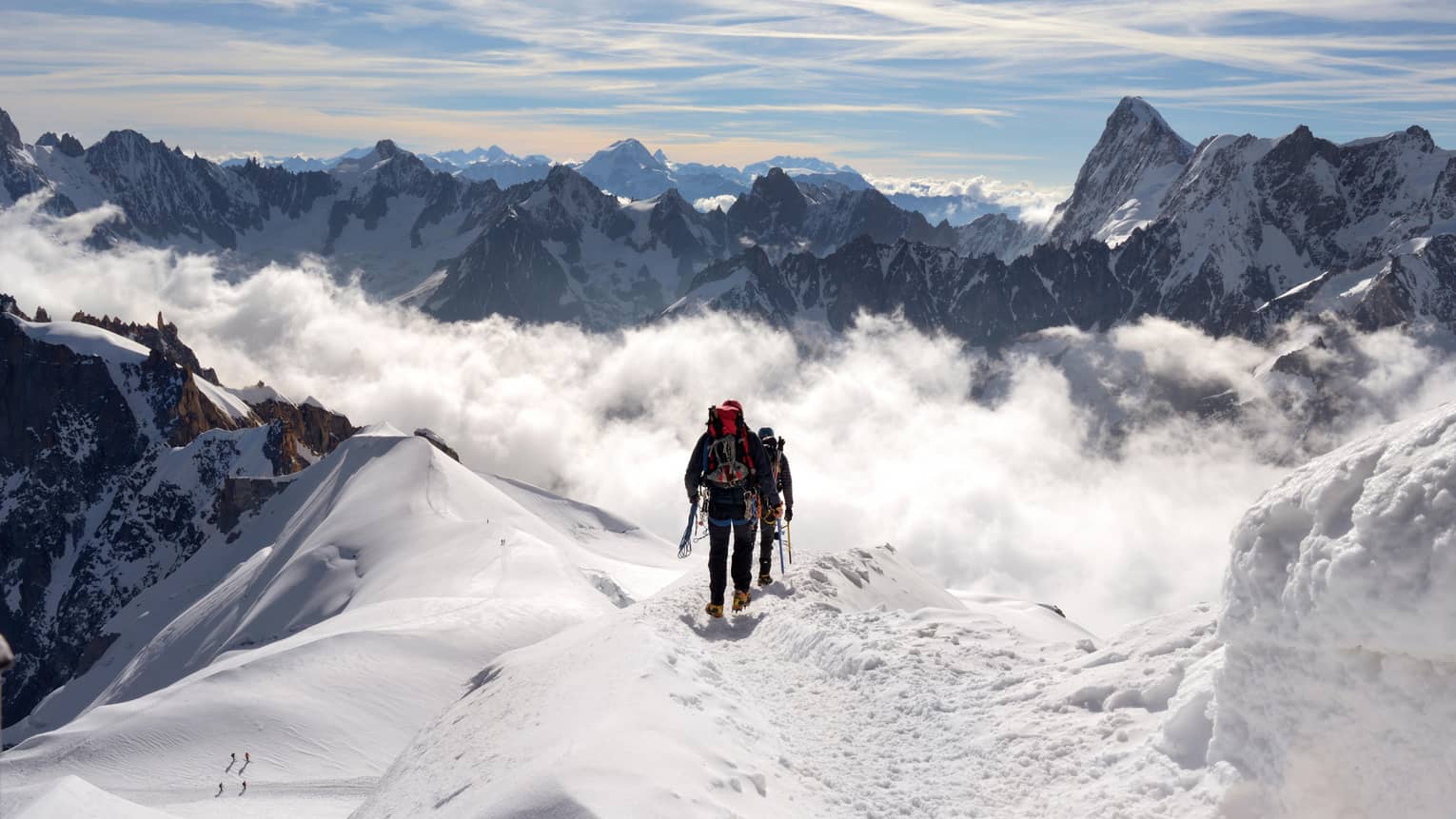 Two people hiking at top of icy mountain in French Alps
