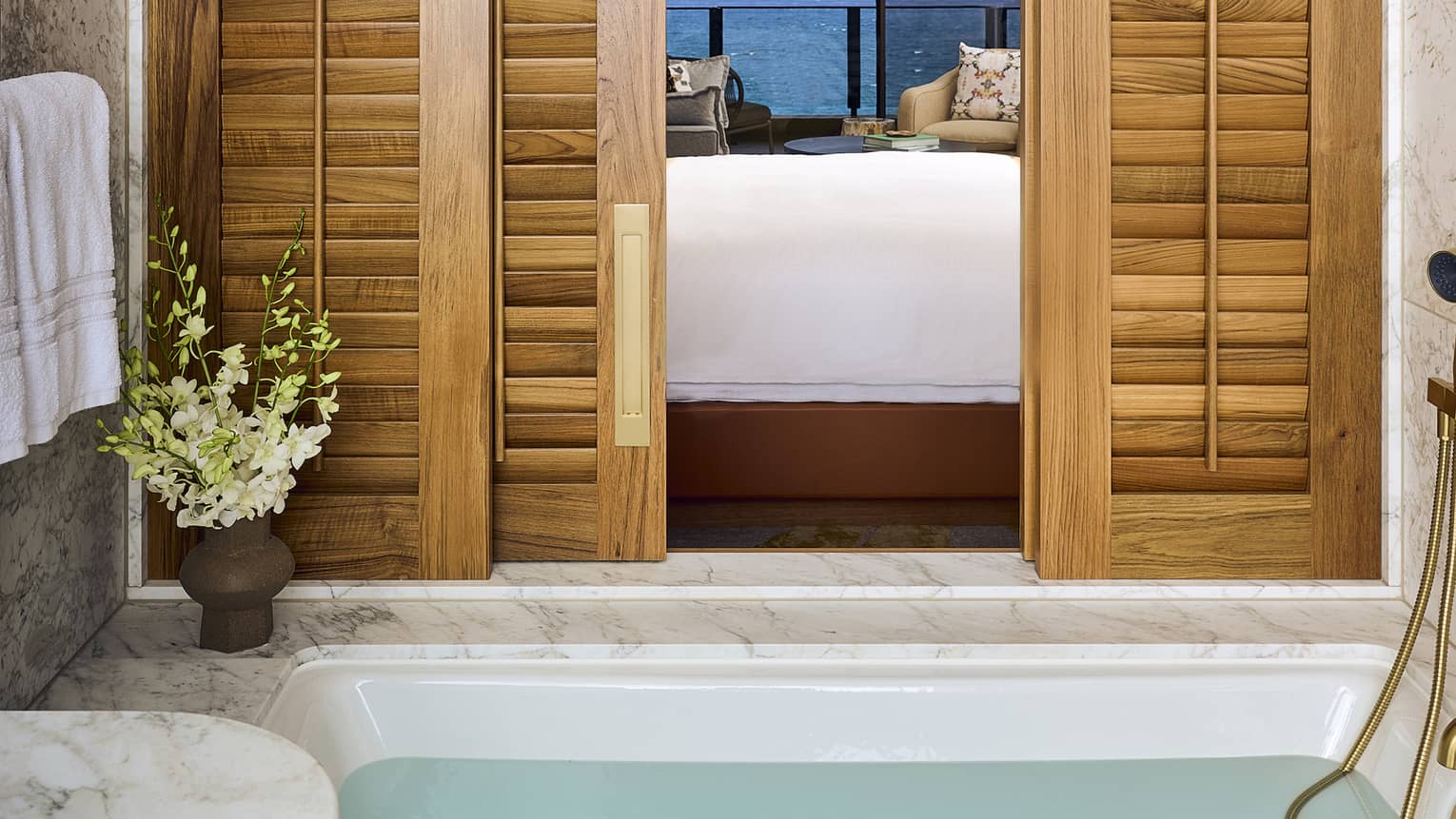 View from a bathroom with marble tub, looking through a bedroom and out to ocean view