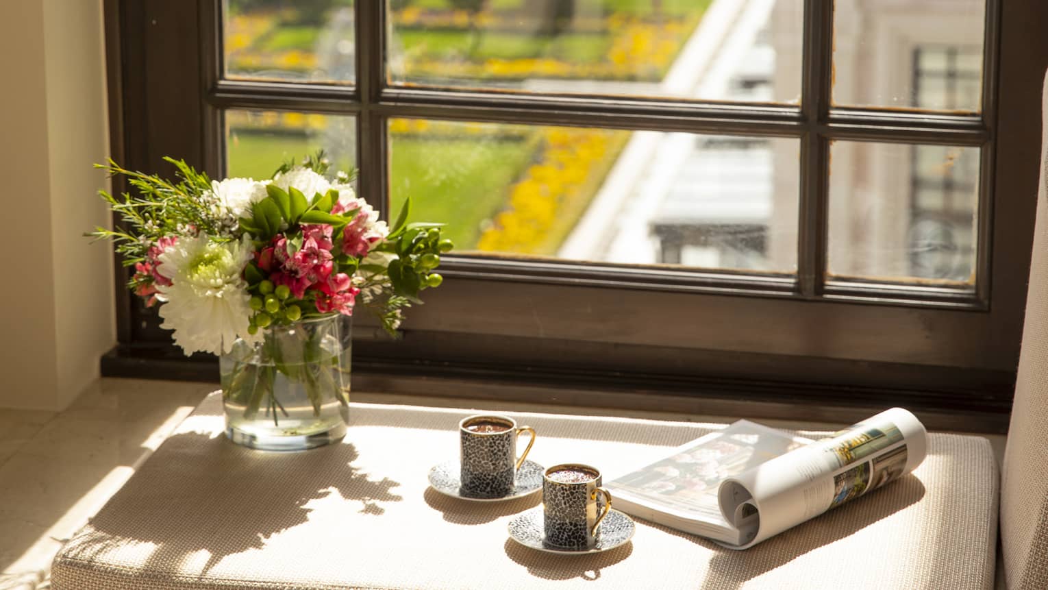 A tray of Turkish coffee, a newspaper and fresh flowers on the windowsill of a guest room, overlooking the city