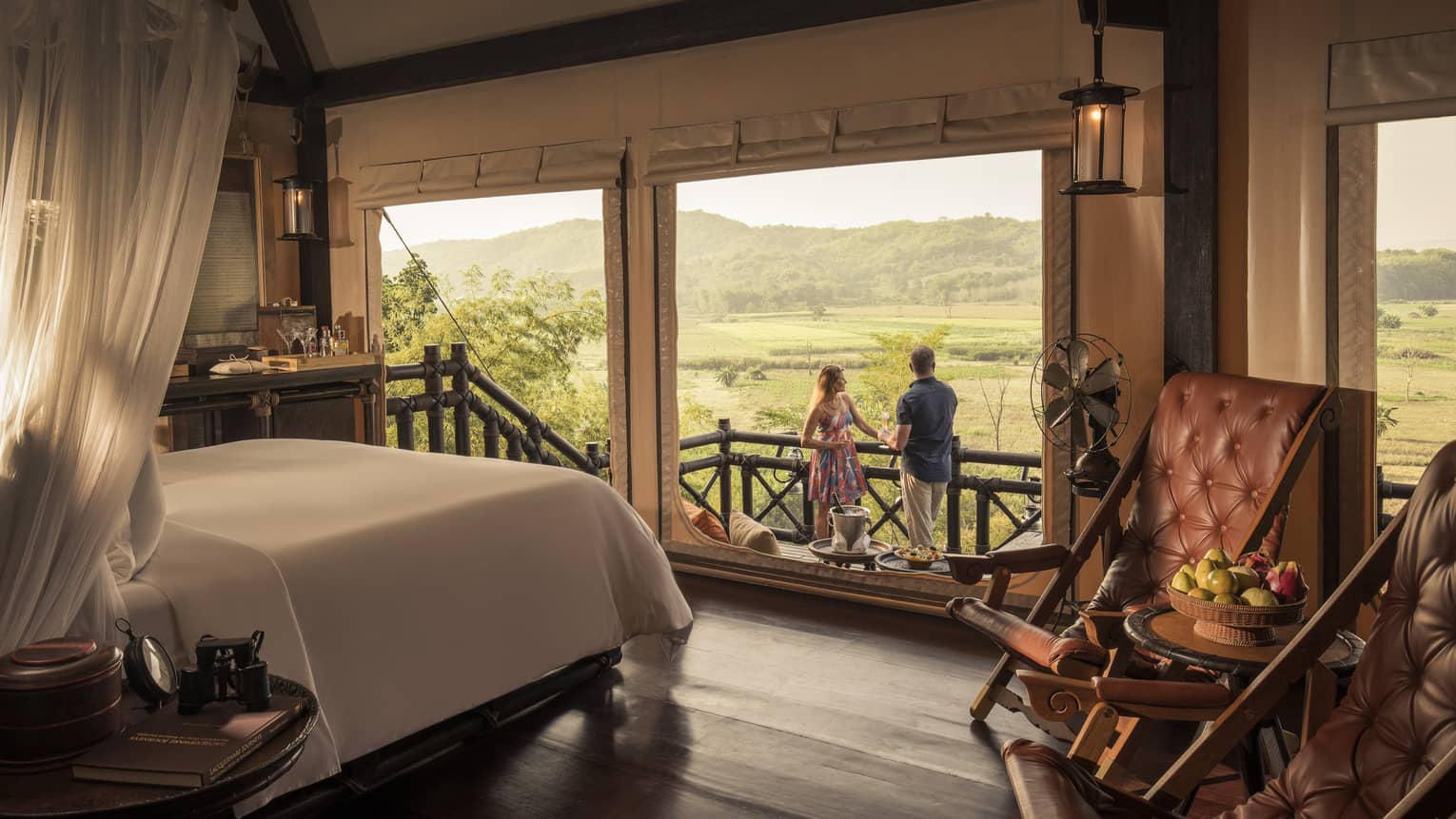 Couple enjoys cocktails overlooking fields and mountains