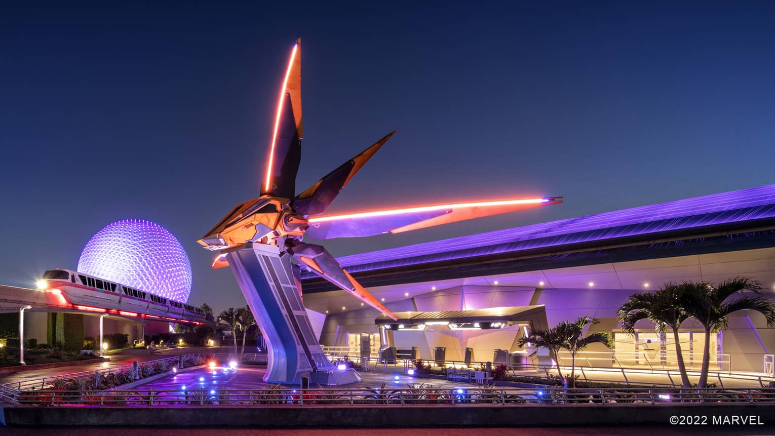 An orange and black sci-fi spaceship resting on a tall pedestal with a tram moving near it.