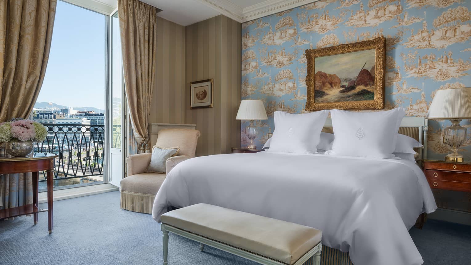 Suite Léman with antique-style blue wallpaper, painting with gold frame above bed next to open French doors with lake view
