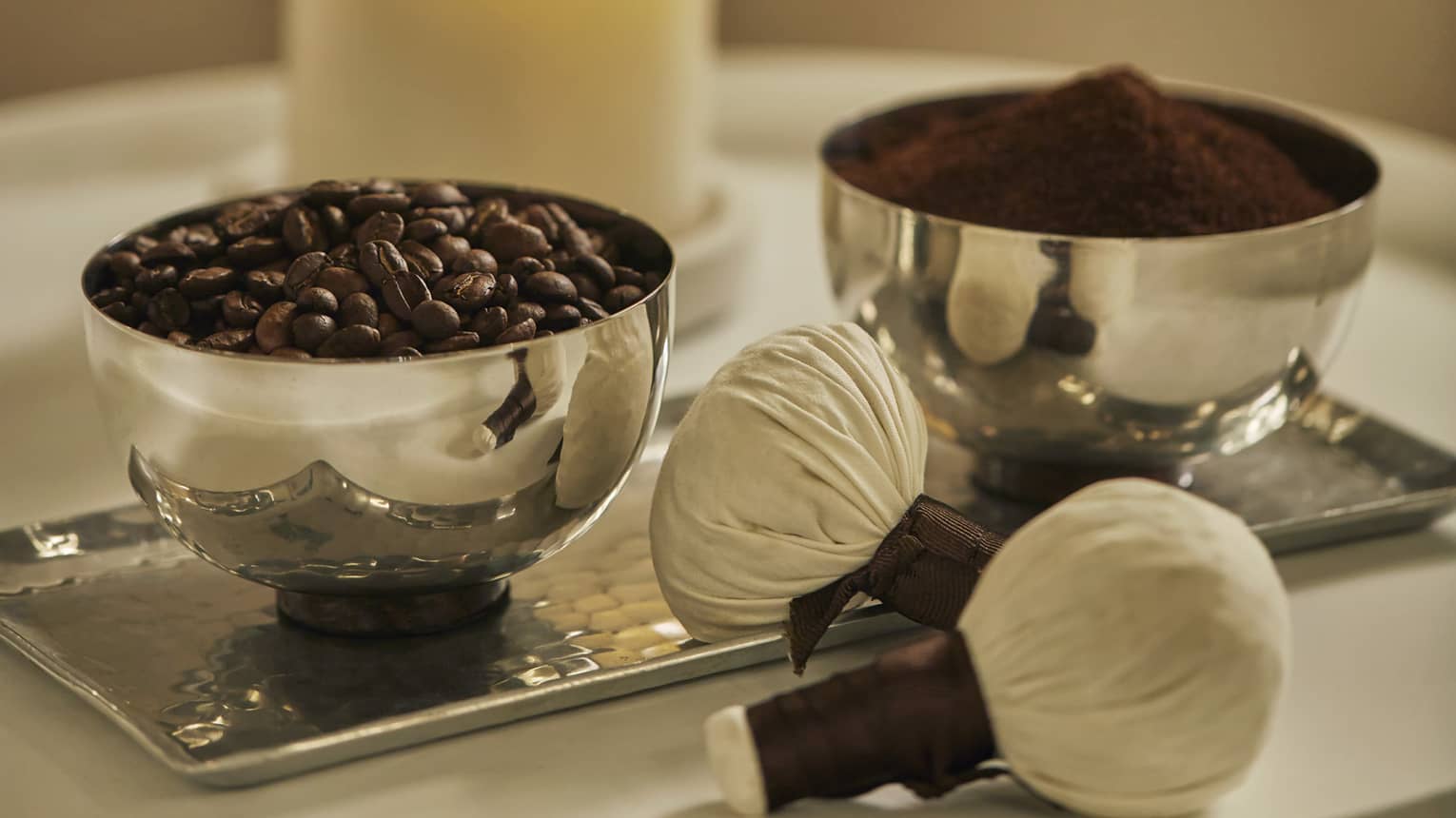silver bowls on tray hold roasted coffee beans, ground coffee