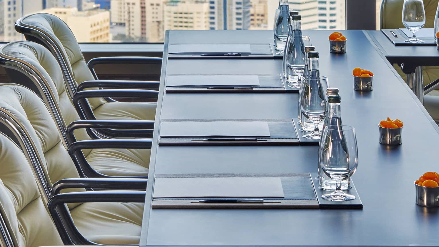 Close-up of meeting table with water, orange flowers by sunny window
