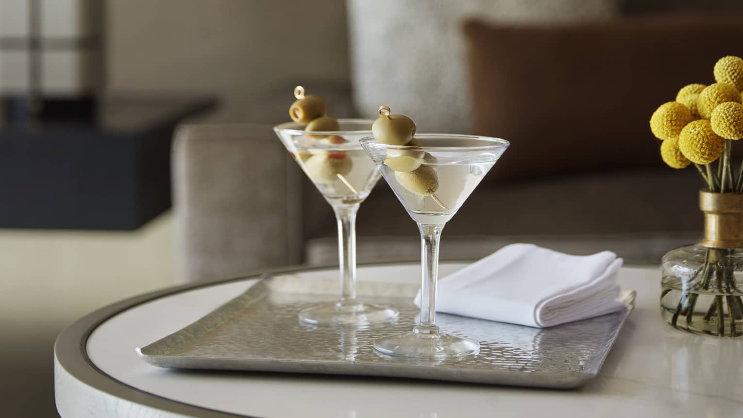 Two cocktail on a small table near a sofa.
