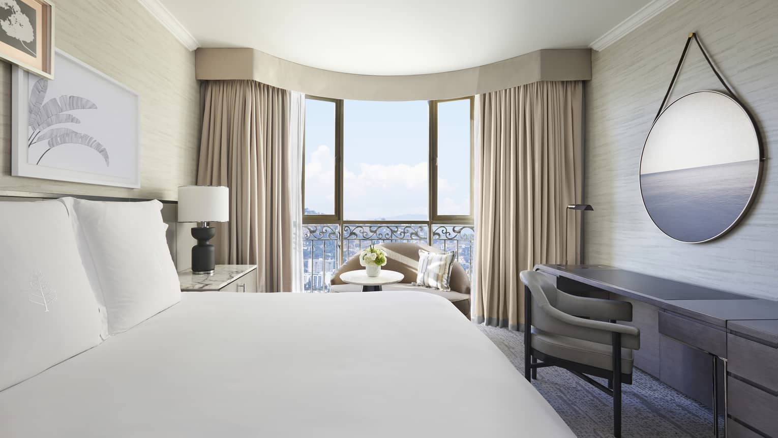 Hotel room with king bed and curved window, beige curtains