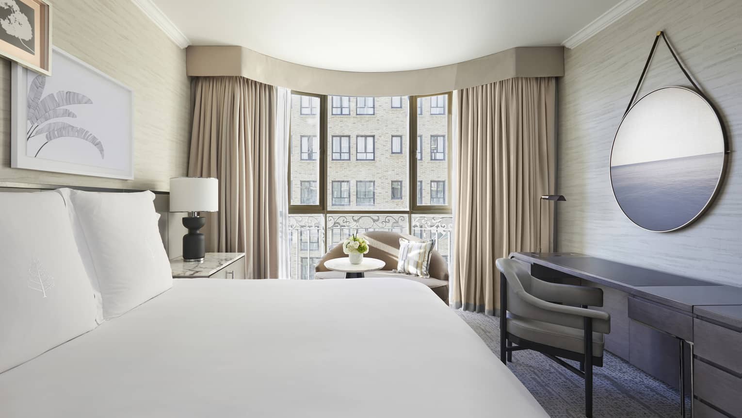 Hotel room with king bed and curved windows looking out to neighbouring building