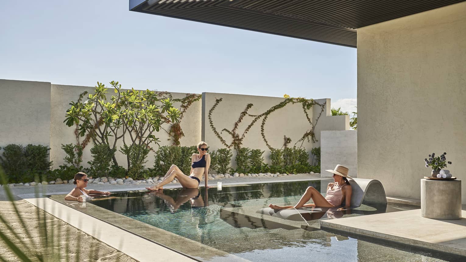 Three women lounging around a small outdoor pool.