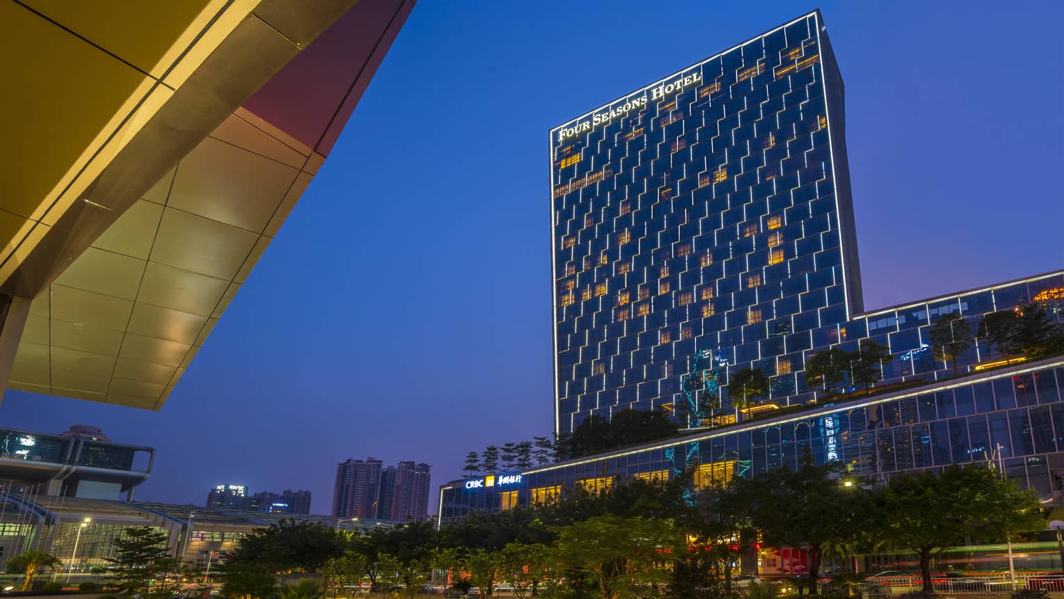 Four Seasons Hotel Shenzhen glass high rise building with lights at dusk
