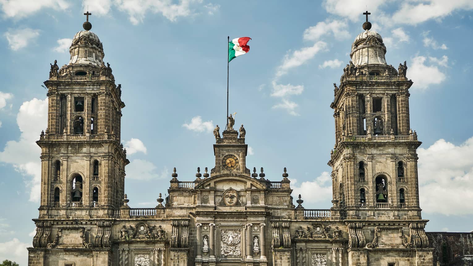 Historic Mexico City building, towers with flag against blue sky