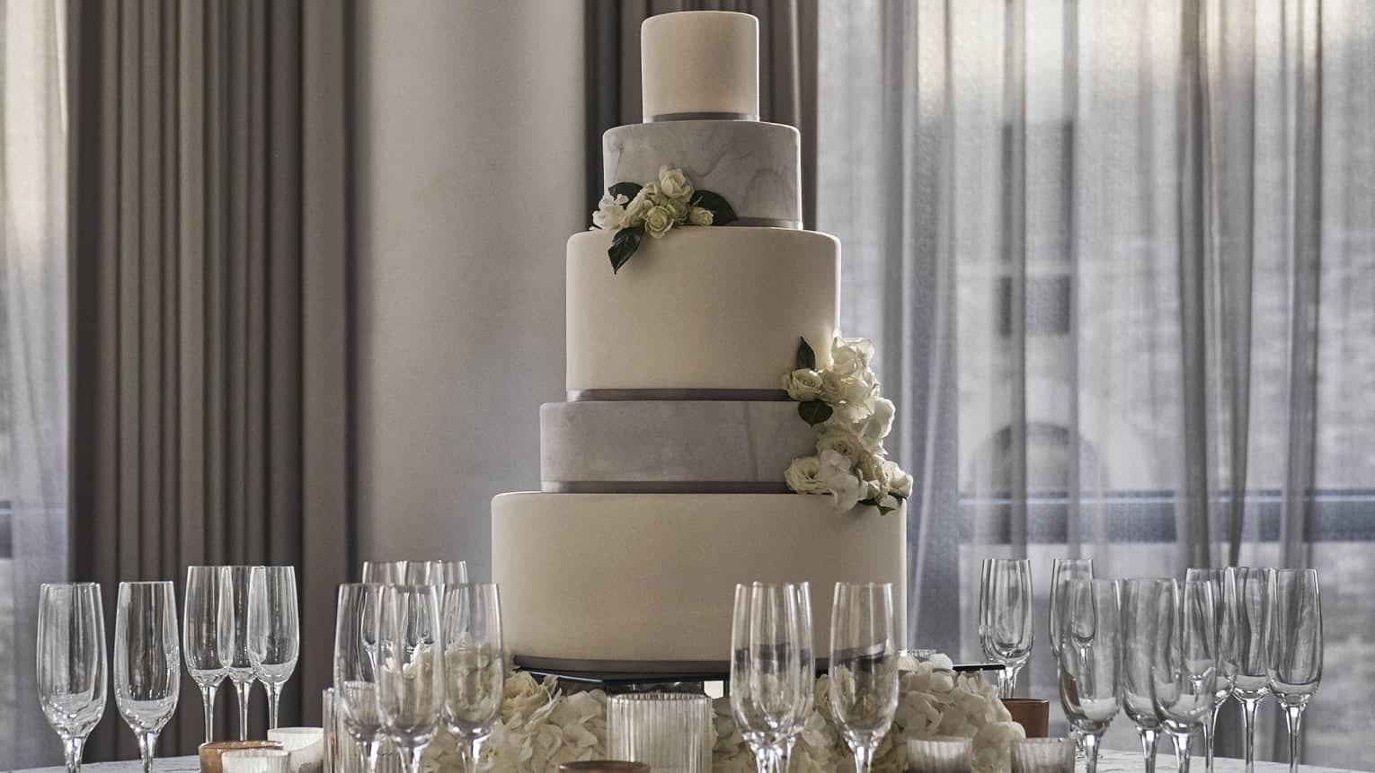 Tiered wedding cake on round banquet table with Champagne glasses