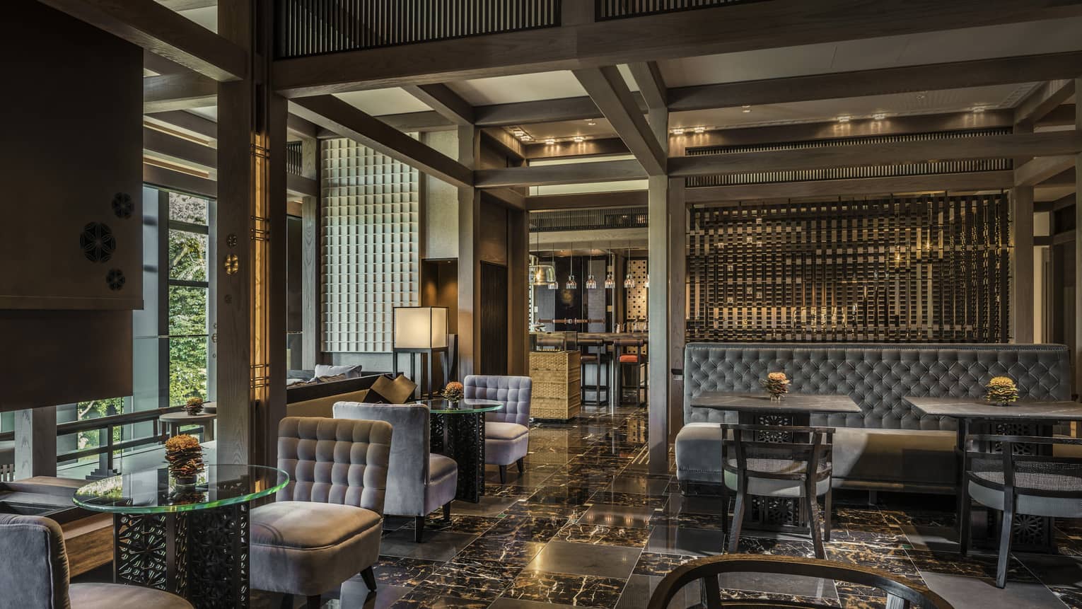 Plush grey velvet sofas, chairs on black marble floors in The Lounge dining room