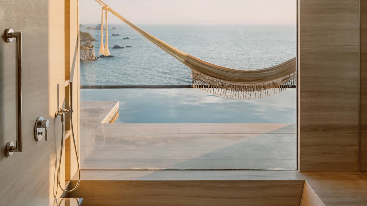 A bathroom opens to an ocean-view terrace with pool and hammock