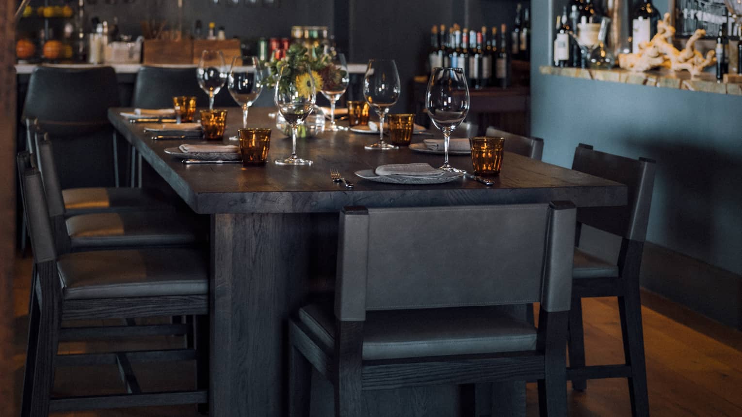 Dining room with candle light chandeliers and shelves of wine bottles.