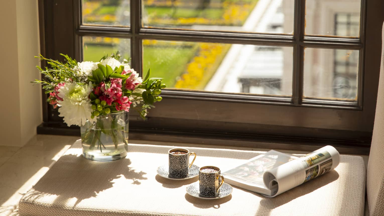A tray of Turkish coffee, a newspaper and fresh flowers on the windowsill of a guest room, overlooking the city