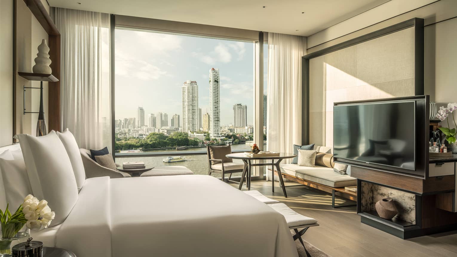 Hotel room with white king bed, view of Chao Phraya River, TV