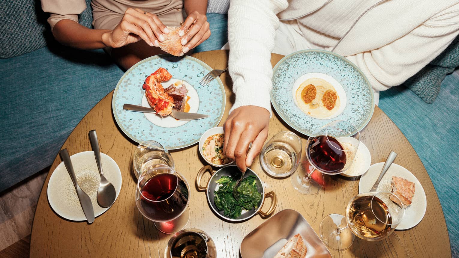 Two people sitting at a table with various food and drinks.