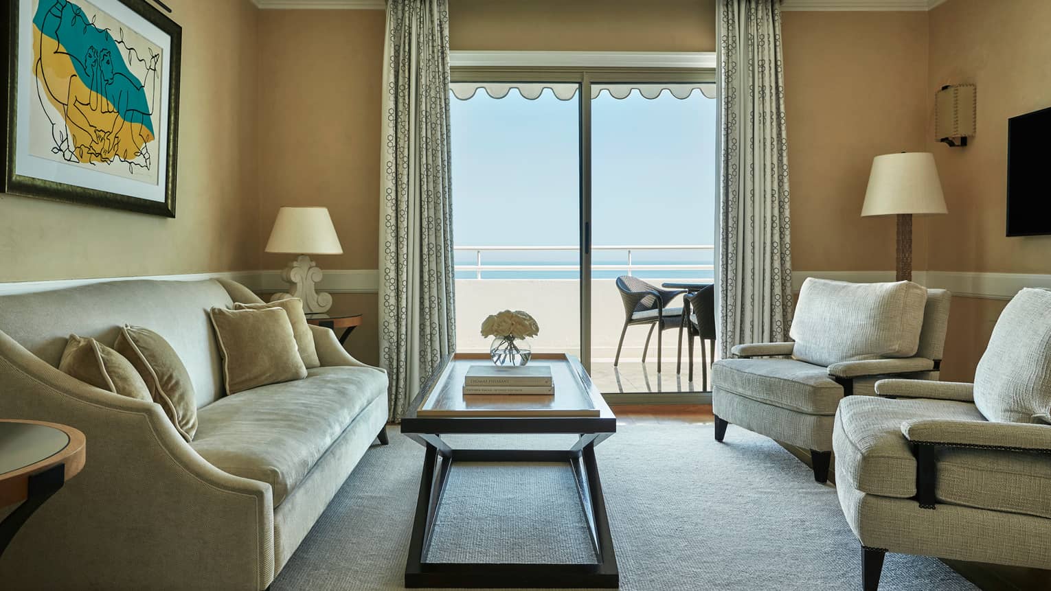 Rooftop Suite beige sofa, armchairs, table by glass sliding doors to balcony