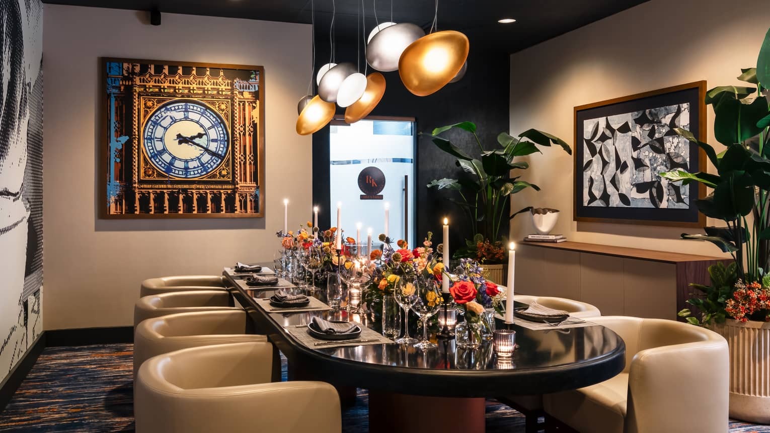 Dining room with lights hanging from the ceiling and artwork on the wall, with a dining table set with flowers and candles