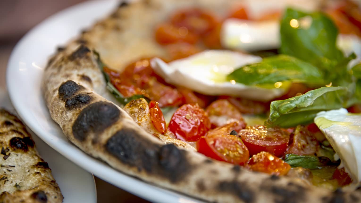 Close-up of Al Fresco signature pizza thin wheat crust, fresh cherry tomatoes, basil
