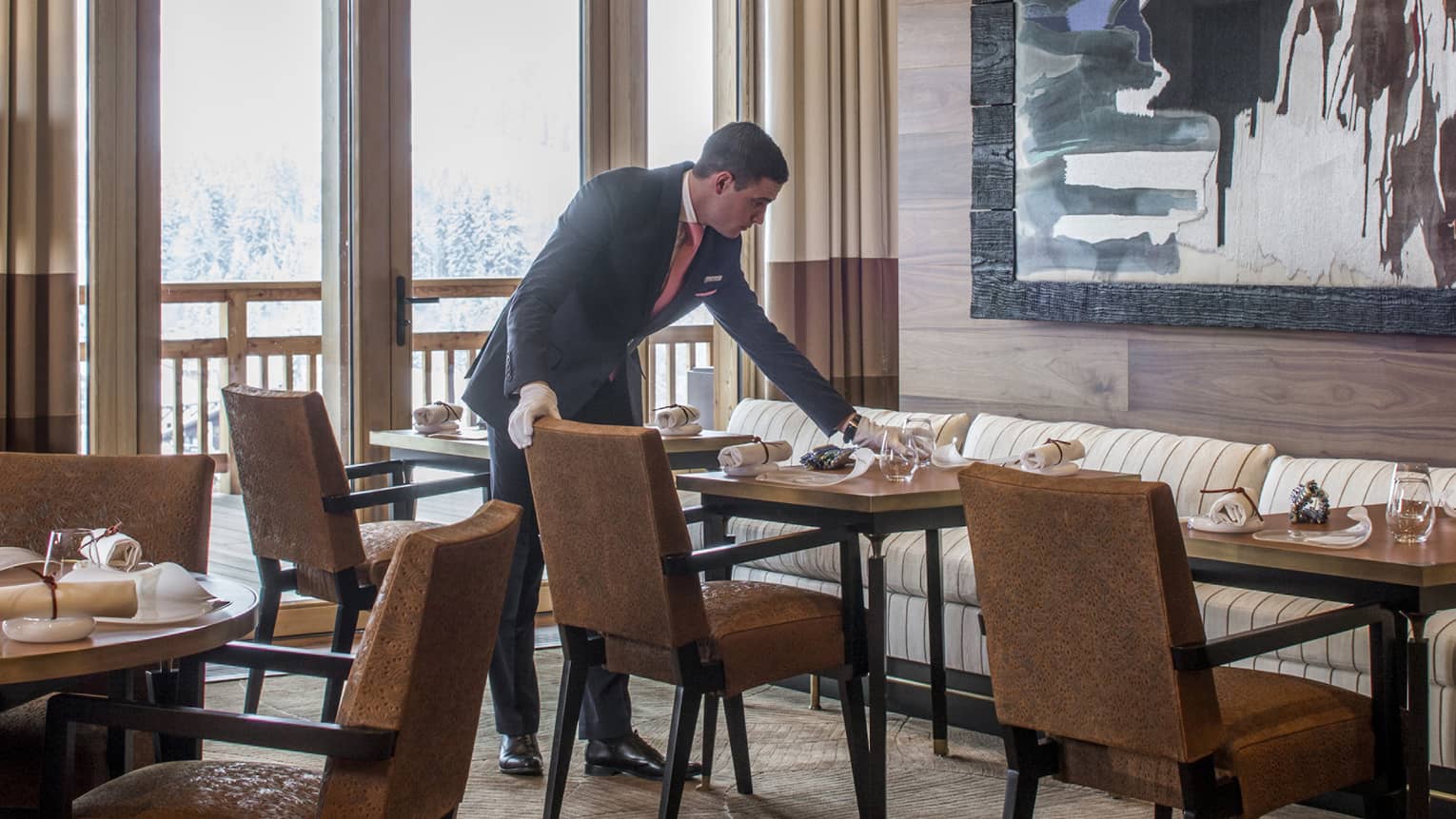 Server sets dining table under large, framed abstract painting in Le 1920 restaurant