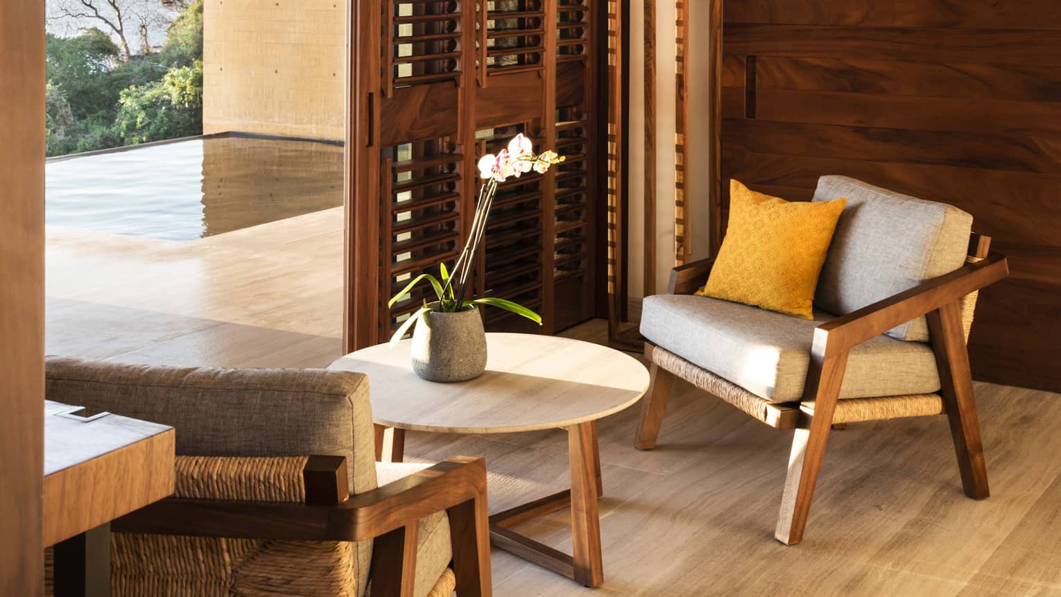 Two arm chairs, a small table, positioned next to pool terrace