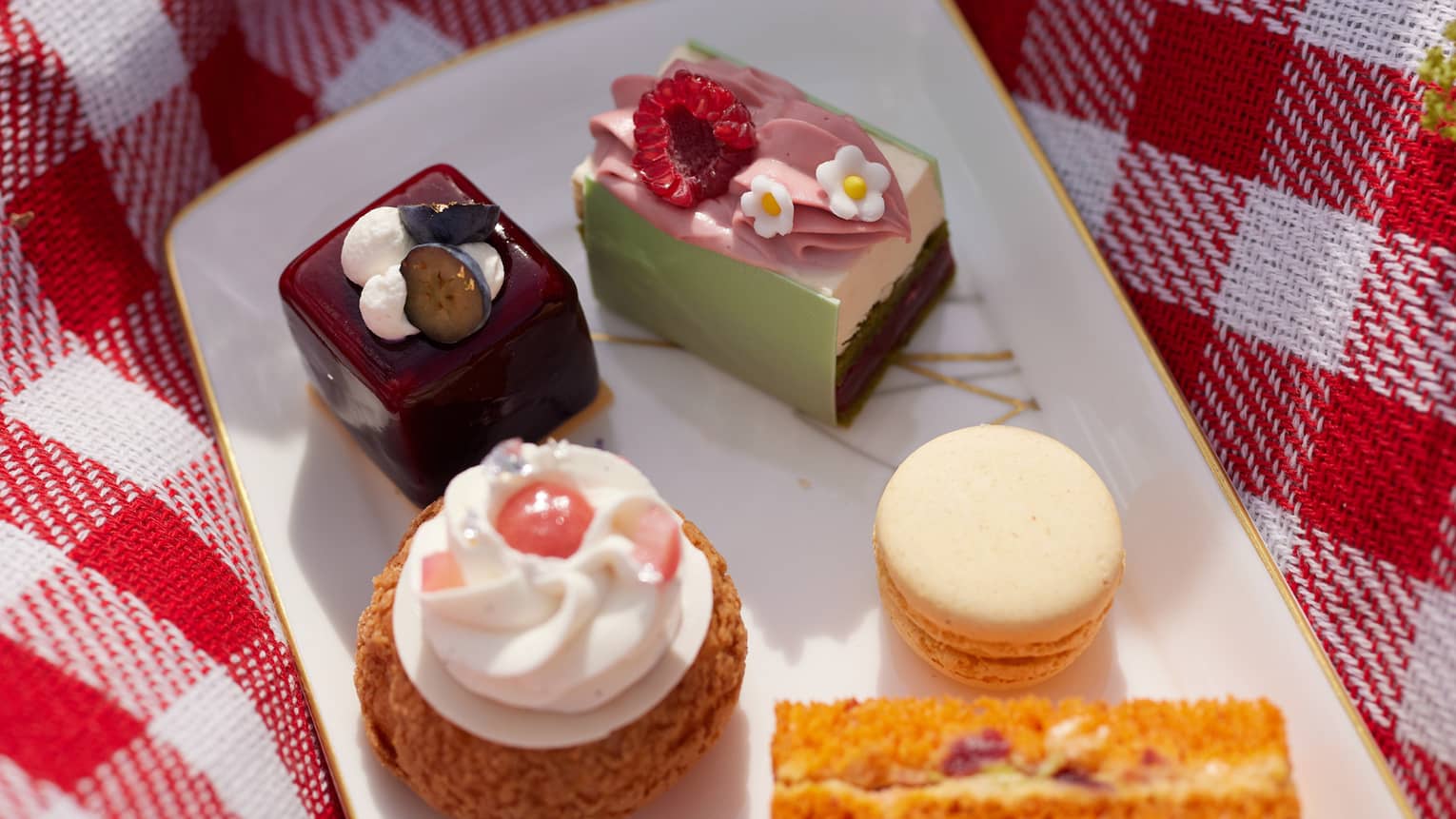 Desserts on a plate placed on a picnic blanket and a bottle of wine beside it
