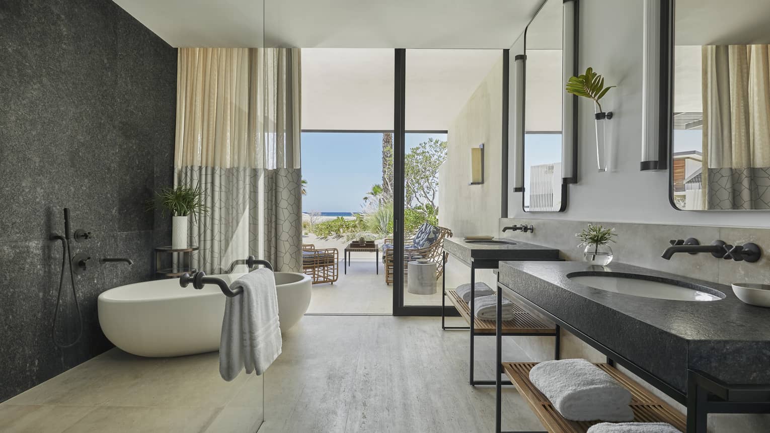 A bathroom with two sinks, a bathrub, and large windows.