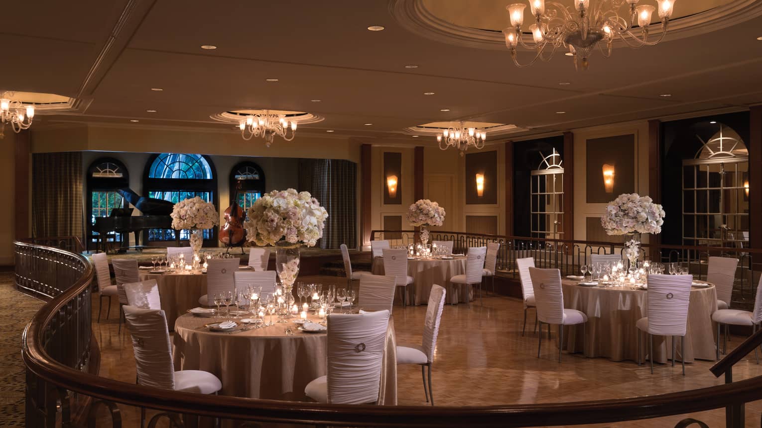 Elegant wedding reception tables with white chairs, flowers on ballroom floor