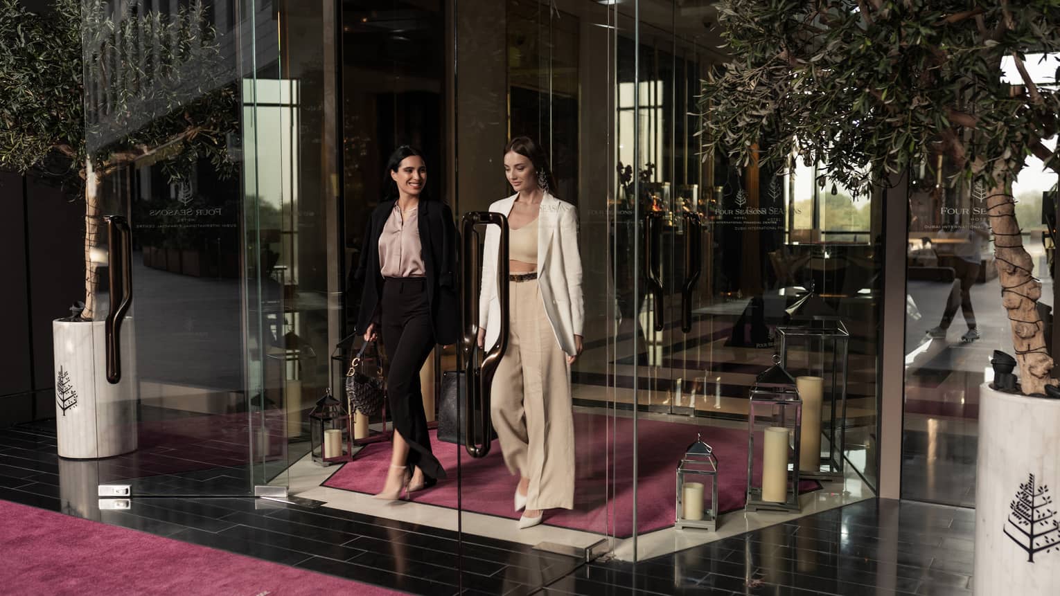 Two women in business attire walking out of a nice hotel