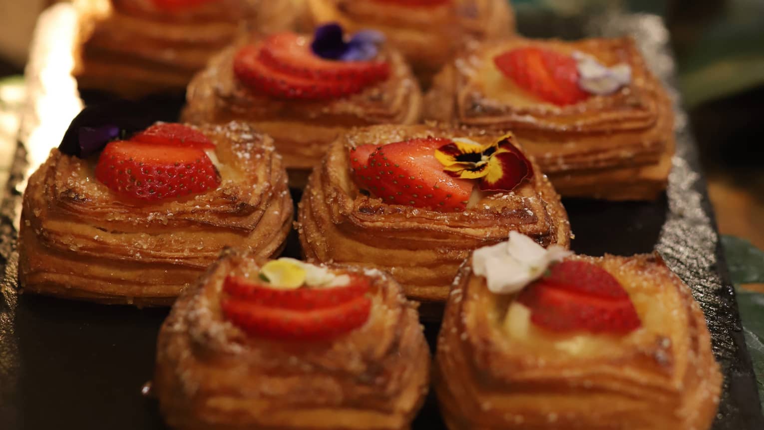Pastries topped with sliced strawberries aligned two-by-two on a brunch display
