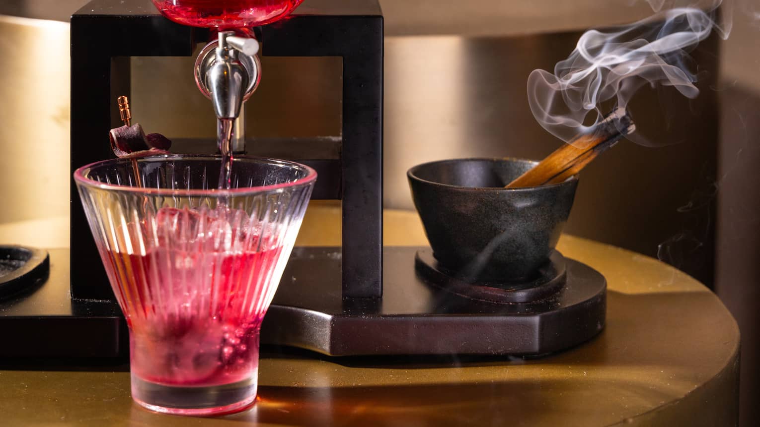 A red cocktail coming out a glass skull.