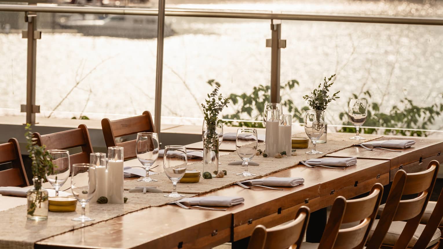 A table with an umbrella set with glasses and flowers, near the water