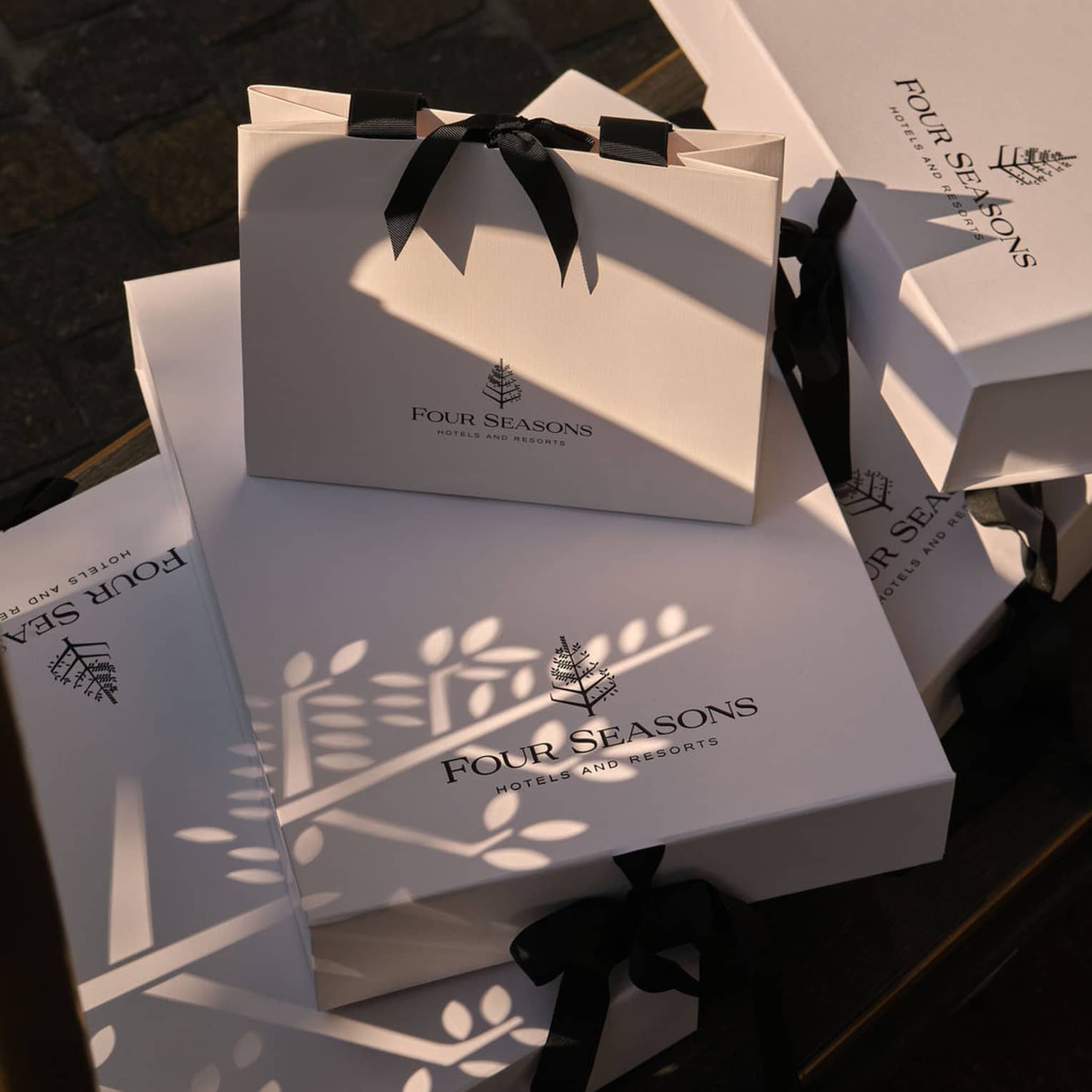 White gift boxes and bags with black bows and the Four Seasons logo