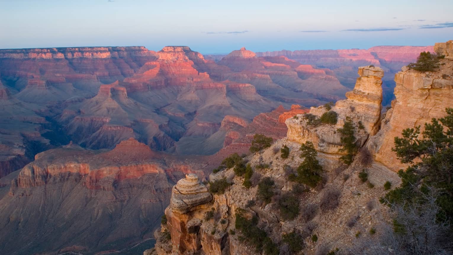 Sweeping view of Grand Canyon cliffs, canyon ridges, pink light from sunset