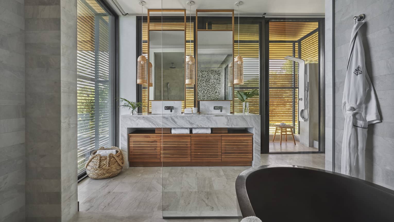 Large marble bathroom with black freestanding tub, entrance to outside