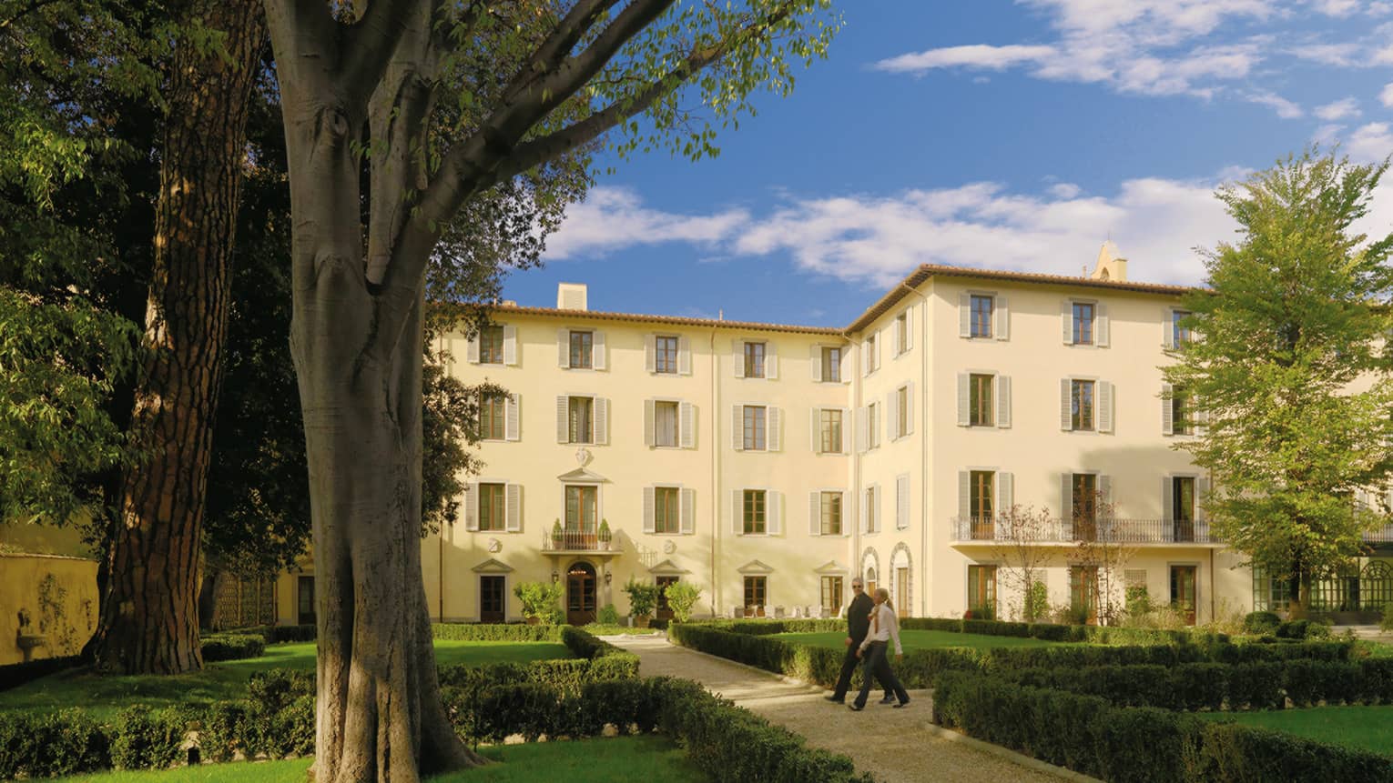 Couple strolls along path in garden courtyard outside Four Seasons Hotel Florence