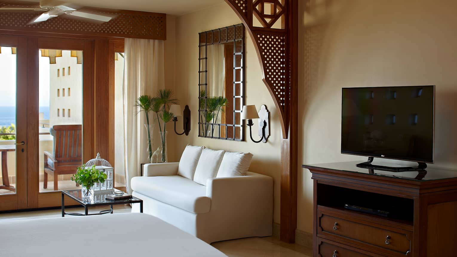 TV, white loveseat sofa by balcony window